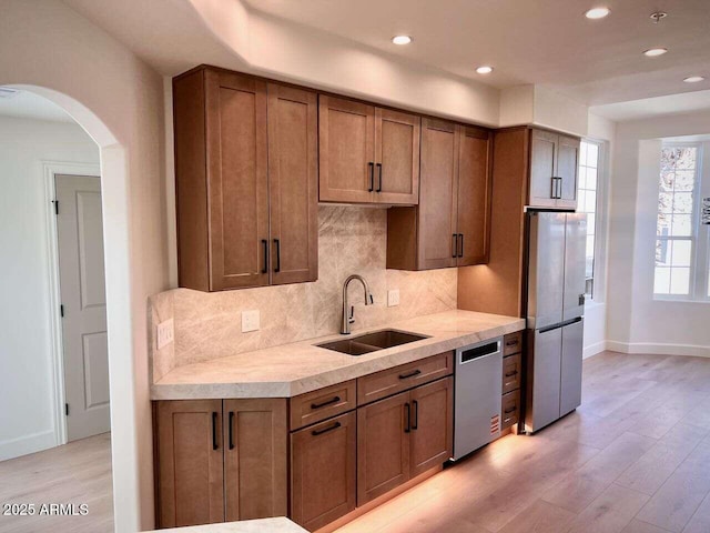 kitchen featuring light wood-style flooring, a sink, stainless steel appliances, light countertops, and tasteful backsplash