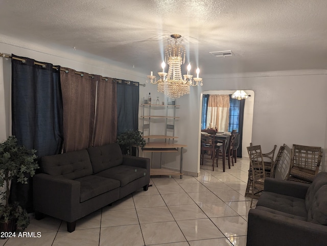 living room with light tile floors, a notable chandelier, and a textured ceiling