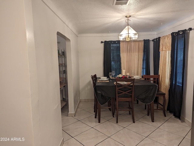 tiled dining area with a notable chandelier and a textured ceiling