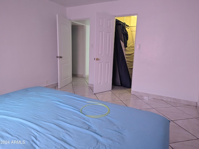 unfurnished bedroom featuring a spacious closet, light tile floors, and a closet