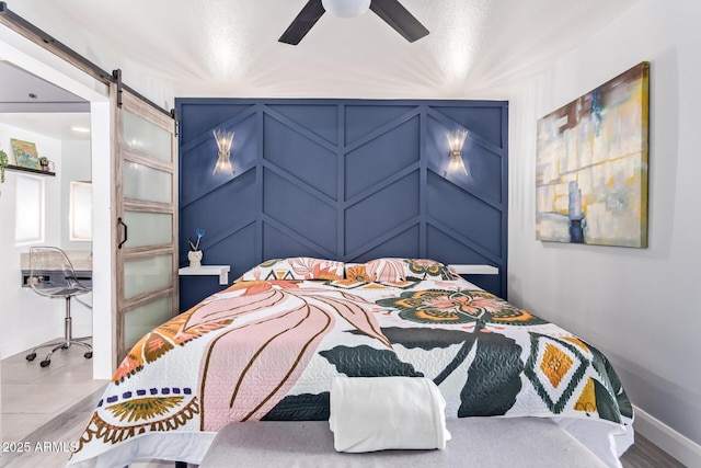 bedroom with a barn door and ceiling fan