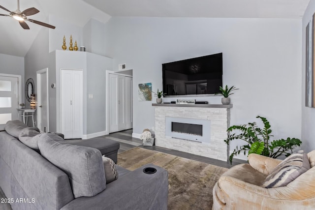 living room with ceiling fan, wood-type flooring, a fireplace, and high vaulted ceiling