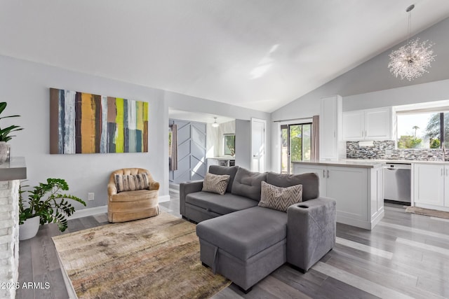 living room featuring a notable chandelier, vaulted ceiling, and light hardwood / wood-style floors