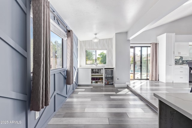 interior space featuring hardwood / wood-style flooring, wine cooler, and a textured ceiling