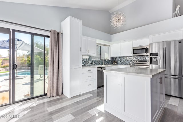 kitchen featuring a center island, appliances with stainless steel finishes, pendant lighting, decorative backsplash, and white cabinets