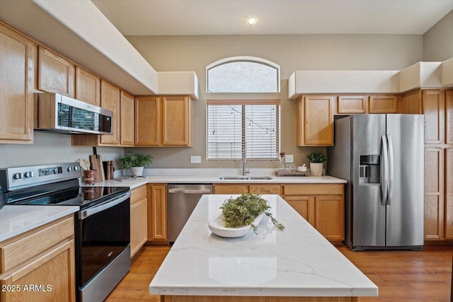 kitchen with a kitchen island, light hardwood / wood-style floors, sink, and appliances with stainless steel finishes