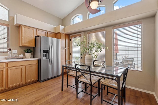 kitchen featuring stainless steel fridge, light wood-type flooring, and a high ceiling