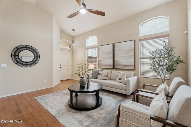 living room with a wealth of natural light, ceiling fan, light hardwood / wood-style floors, and lofted ceiling