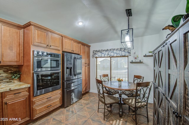 kitchen featuring appliances with stainless steel finishes, decorative light fixtures, light stone countertops, and backsplash