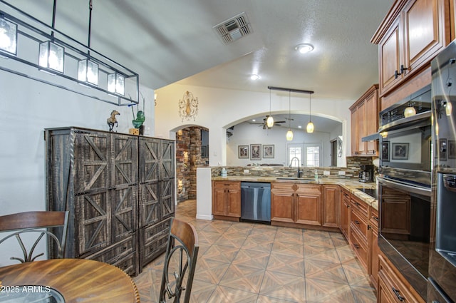 kitchen featuring sink, tasteful backsplash, stainless steel dishwasher, kitchen peninsula, and pendant lighting