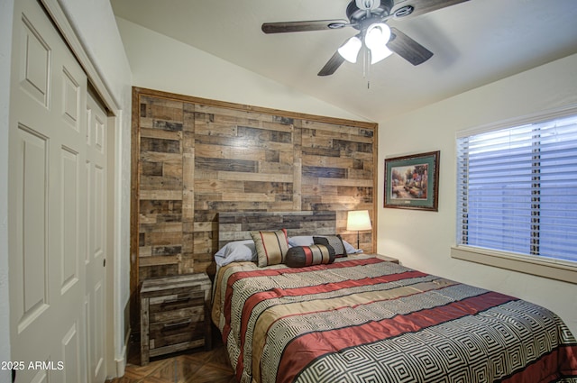 bedroom with ceiling fan, dark parquet flooring, vaulted ceiling, and a closet