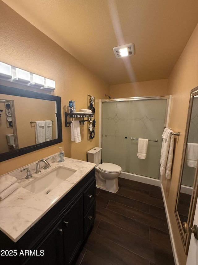 full bathroom with wood finish floors, visible vents, toilet, a shower stall, and vanity