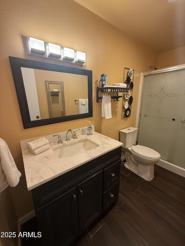 bathroom with vanity, a shower stall, toilet, and wood finish floors