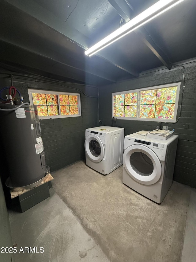 clothes washing area featuring electric water heater, a healthy amount of sunlight, concrete block wall, and washing machine and clothes dryer