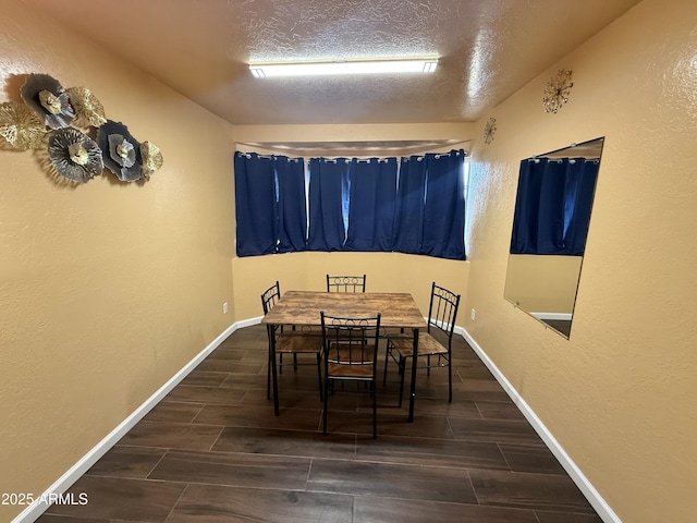 dining room with wood finish floors, baseboards, a textured ceiling, and a textured wall