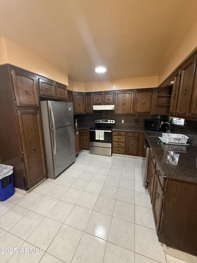 kitchen with under cabinet range hood, open shelves, a sink, stainless steel appliances, and dark brown cabinetry