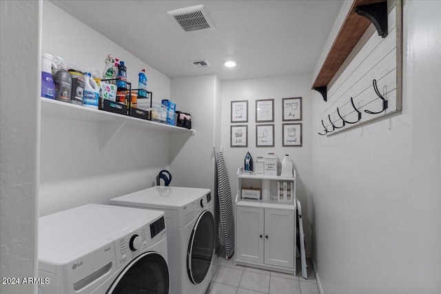 laundry room featuring washing machine and dryer, cabinets, and light tile patterned floors