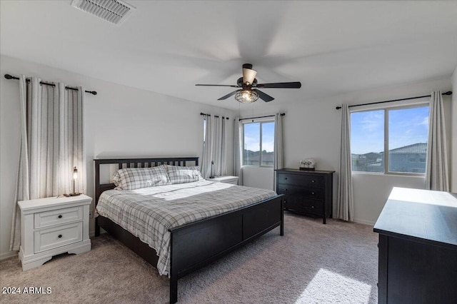 bedroom with multiple windows, ceiling fan, and carpet floors