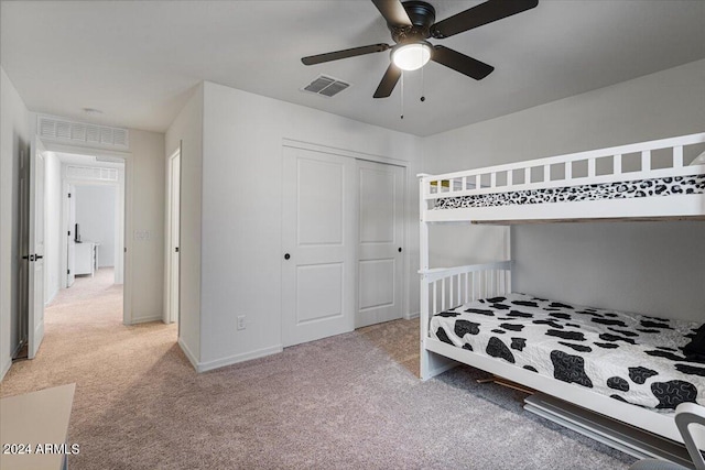 bedroom featuring light carpet, ceiling fan, and a closet