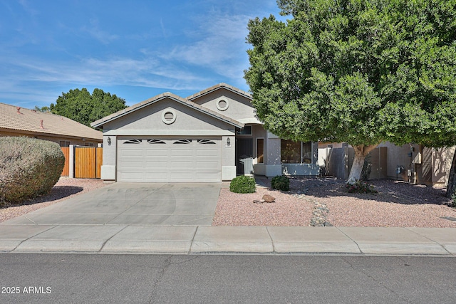 view of front of property with a tile roof, stucco siding, an attached garage, fence, and driveway