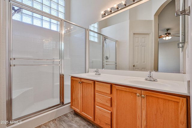 bathroom with a ceiling fan, a stall shower, a sink, and double vanity