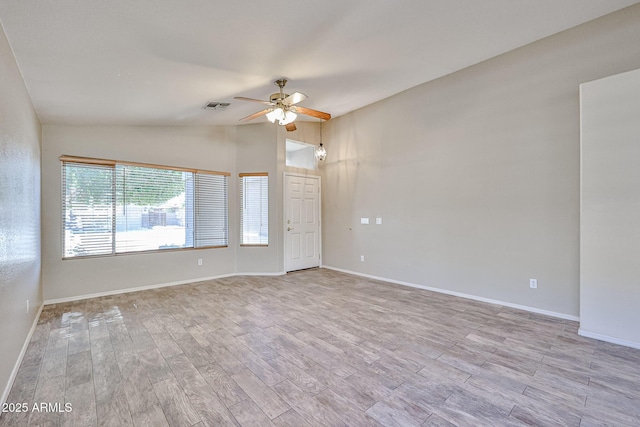 spare room with baseboards, visible vents, a ceiling fan, lofted ceiling, and light wood-type flooring