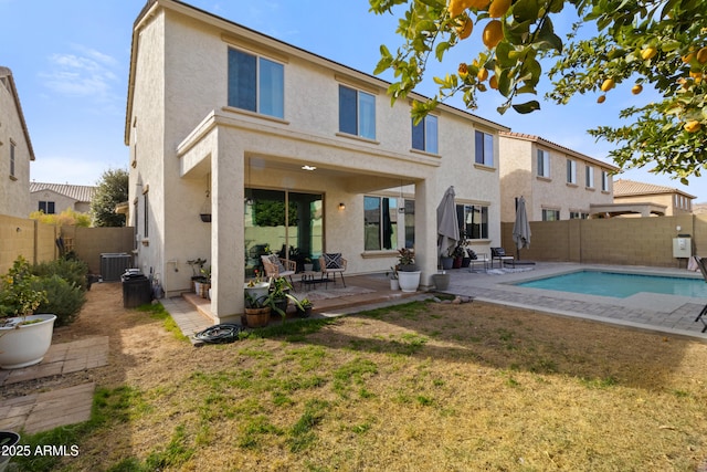 rear view of property with a fenced in pool, a patio, cooling unit, and a lawn