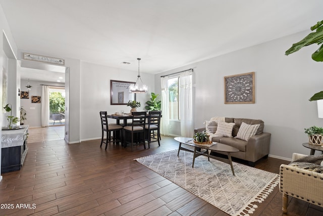 living room featuring an inviting chandelier and dark wood-type flooring