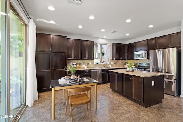 kitchen featuring stainless steel appliances, a kitchen island, dark brown cabinets, and decorative backsplash