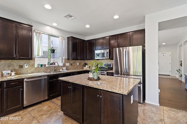 kitchen with stainless steel appliances, a center island, sink, and dark brown cabinetry