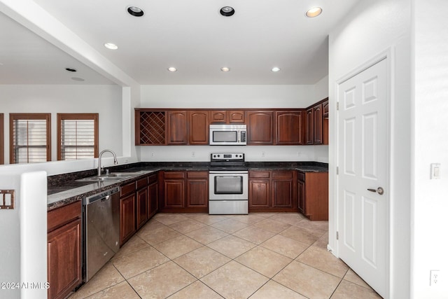 kitchen with light tile patterned flooring, sink, stainless steel appliances, and dark stone counters