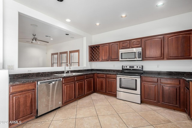 kitchen featuring sink, ceiling fan, dark stone countertops, appliances with stainless steel finishes, and light tile patterned flooring