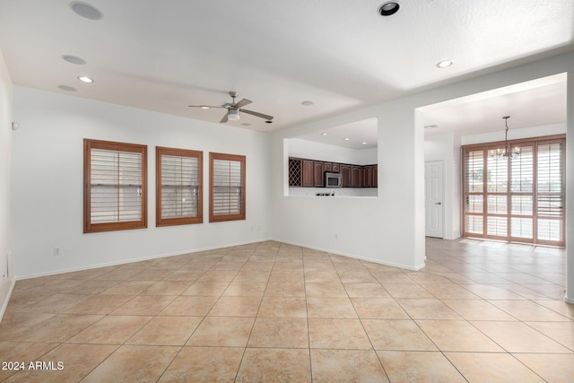 unfurnished living room featuring light tile patterned floors and ceiling fan with notable chandelier