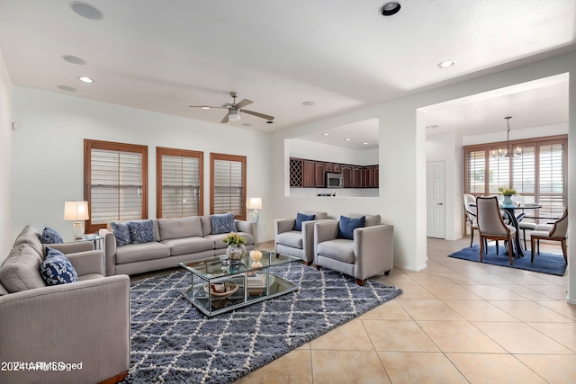 tiled living room featuring ceiling fan with notable chandelier