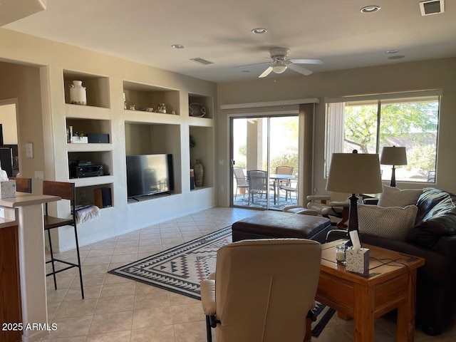 living area with visible vents, a ceiling fan, built in features, and light tile patterned floors