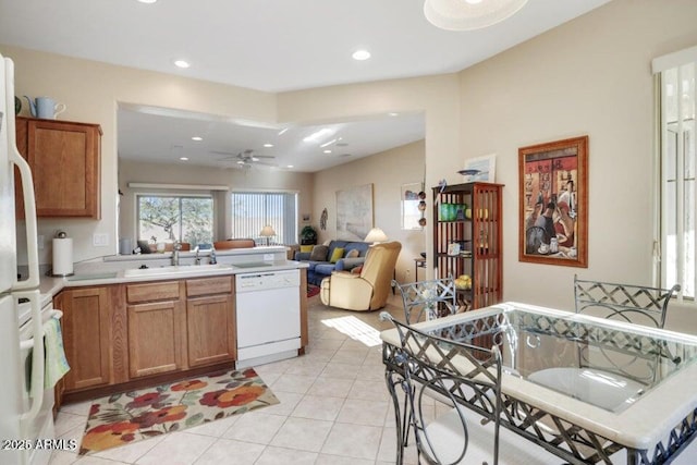 kitchen with a peninsula, white dishwasher, ceiling fan, a sink, and range