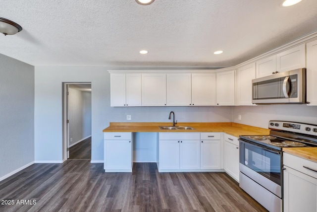 kitchen featuring appliances with stainless steel finishes, dark wood finished floors, a sink, and wood counters