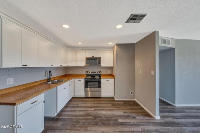 kitchen featuring visible vents, wood counters, appliances with stainless steel finishes, and a sink