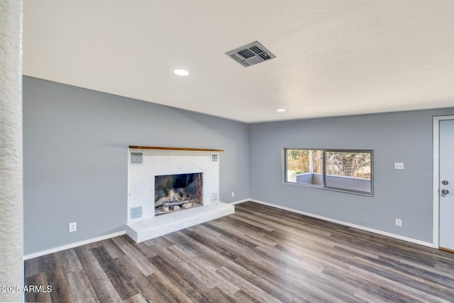 unfurnished living room featuring wood finished floors, visible vents, baseboards, and a premium fireplace