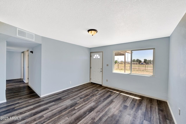 interior space featuring a textured ceiling, wood finished floors, visible vents, and baseboards