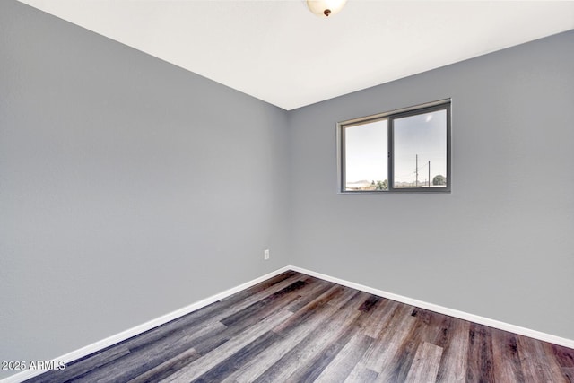 unfurnished room featuring baseboards and dark wood-type flooring