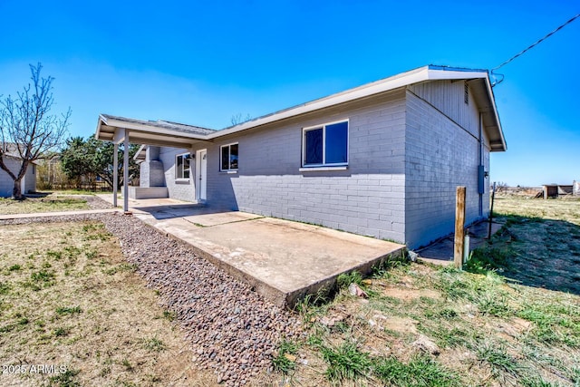 ranch-style house featuring a patio and concrete block siding