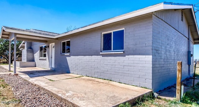 view of side of home with a patio and concrete block siding