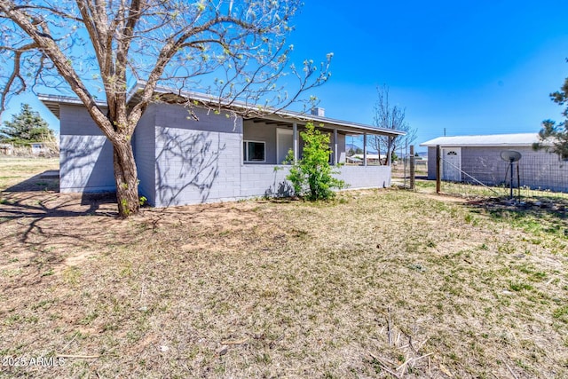 rear view of house featuring fence and a lawn