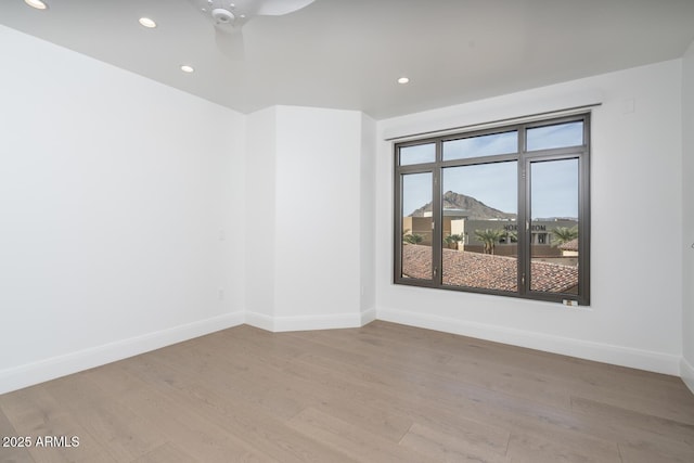 unfurnished room featuring a mountain view, light hardwood / wood-style floors, and ceiling fan