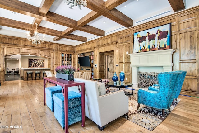 living room with coffered ceiling, wooden walls, light hardwood / wood-style flooring, beamed ceiling, and a chandelier