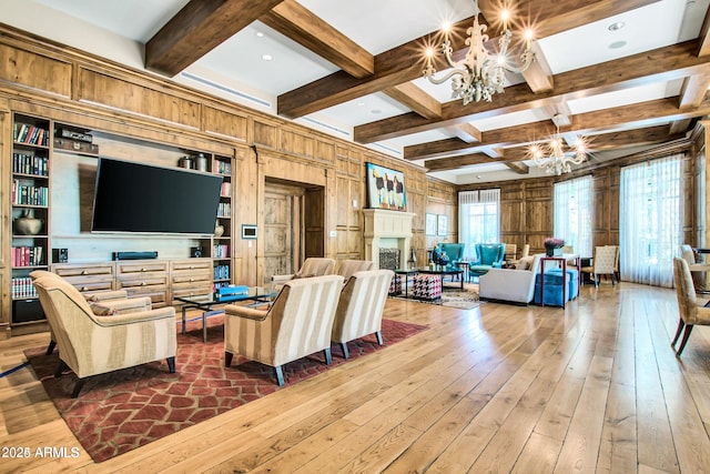 living room featuring built in shelves, coffered ceiling, an inviting chandelier, wood walls, and hardwood / wood-style flooring