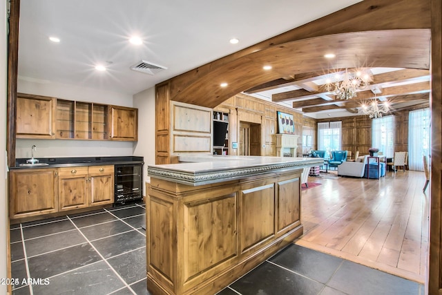 kitchen featuring sink, beverage cooler, beamed ceiling, a notable chandelier, and a kitchen island