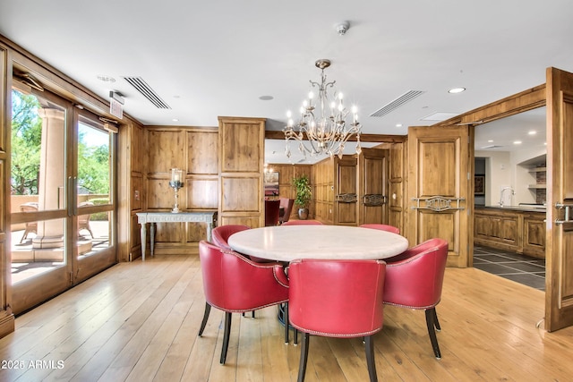 dining area featuring sink, light wood-type flooring, and a notable chandelier