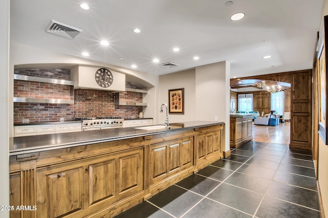 kitchen with dark tile patterned floors, sink, and stainless steel stove